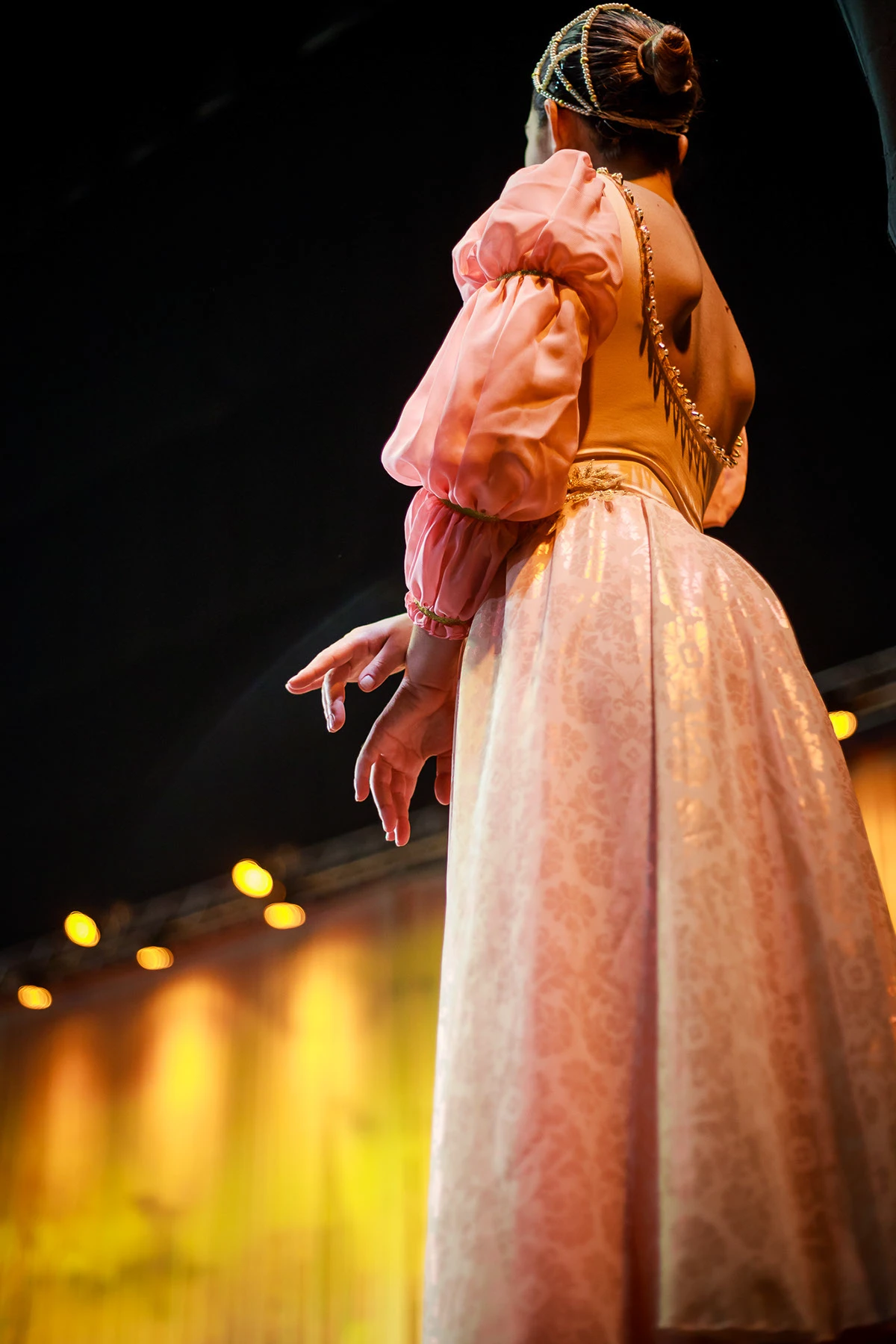 Detalhe de figurino rosa sob luz dourada